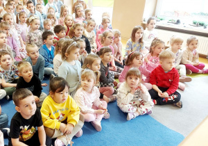 Dzieci siedzą na dywanie w trakcie koncertu wiolonczelowego