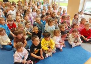 Dzieci siedzą na dywanie w trakcie koncertu wiolonczelowego