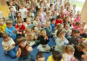 Dzieci siedzą na dywanie w trakcie koncertu wiolonczelowego