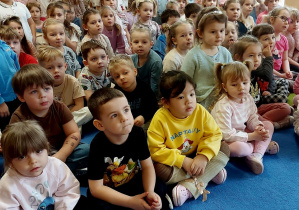 Dzieci siedzą na dywanie w trakcie koncertu