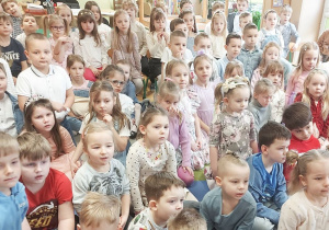 Dzieci siedzą na dywanie w trakcie koncertu