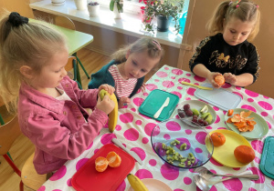 Dziewczynki obierają mandarynki i banana