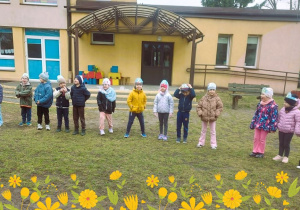 Dzieci stoją ustawione w kole w ogrodzie przedszkolnym