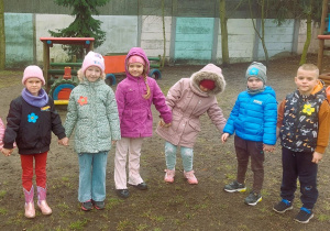 Dzieci stoją trzymając się za ręce w ogrodzie