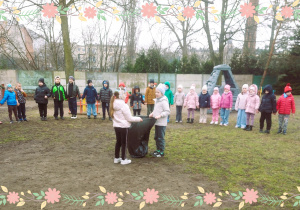 Dzieci wkładają Marzannę do worka w ogrodzie przedszkolnym