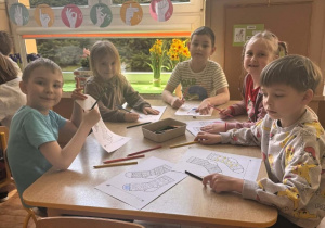 Dzieci siedzą przy stolikach i kolorują