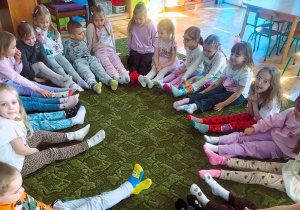 Dzieci siedzą w kole pokazując kolorowe skarpetki na swoich stopach