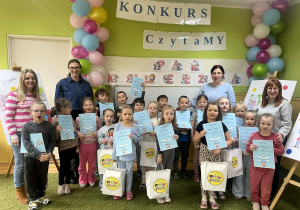 Dzieci pozują do zdjęcia z Komisją konkursową, dyplomami i nagrodami