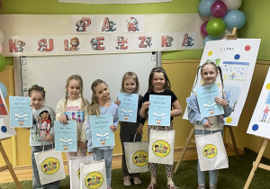 Dzieci pozują do zdjęcia z dyplomami i nagrodami