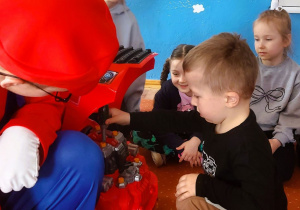 Chłopiec wkręca plastikową śrubę naprawiając samochód