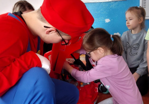 Dziewczynka wkręca plastikową śrubę naprawiając samochód