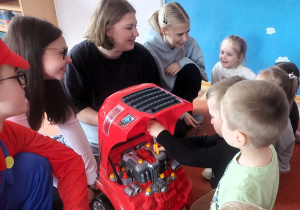 Chłopiec wkręca plastikową śrubę naprawiając samochód