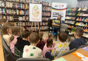 Dzieci na zajęciach w bibliotece słuchają opowiadania o Kotce Psotce