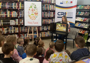 Dzieci na zajęciach w bibliotece słuchają opowiadania o Kotce Psotce