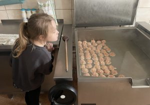 Dziewczynka obserwuje przygotowanie mięsa.