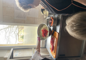 Pani pokazuje przygotowanie sałatki.