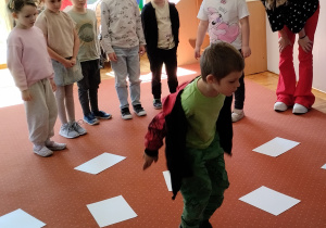 Chłopiec skacz po kartkach papieru ułożonych na dywanie