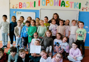 Dzieci pozują do zdjęcia grupowego z autorką wierszy dla dzieci