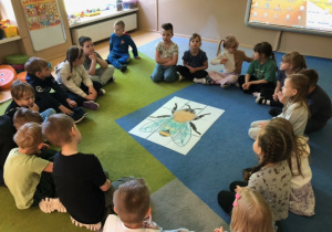 Dzieci siedzą w kole rozmawiają o pszczołach
