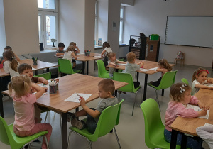 Dzieci siedzą przy stolikach