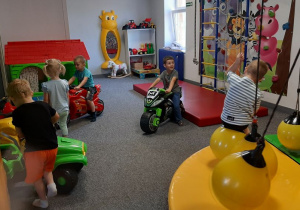Dzieci bawią się w różnorodnych strefach ruchu w sali zabaw