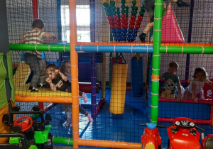 Dzieci bawią się w różnorodnych strefach ruchu w sali zabaw