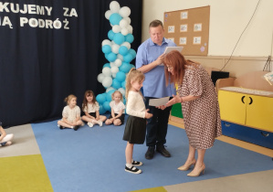 Dziewczynka odbiera dyplom od dyrekcji i wychowawcę