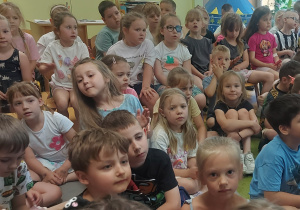 Dzieci w trakcie koncertu muzycznego siedzą na dywanie