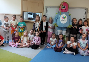 Dzieci pozują do zdjęcia grupowego w sali przedszkolnej