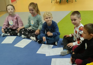 Dzieci siedzą na dywanie w kole