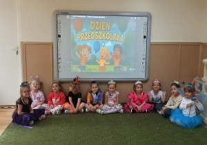Dzieci pozują do zdjęcia grupowego w sali przedszkolnej