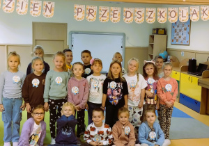 Dzieci pozują do zdjęcia grupowego w sali przedszkolnej