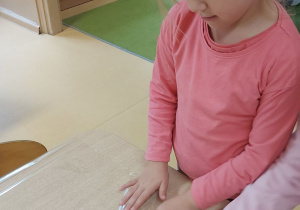 Dzieci przesuwają liście położone pod folią na stoliku