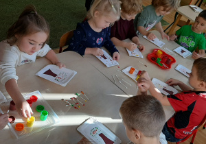 Dzieci malują farbami liście drzew