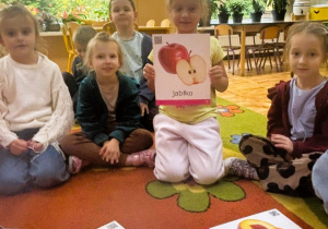 Dzieci oglądają i wskazują ilustracje przedstawiające warzywa i owoce
