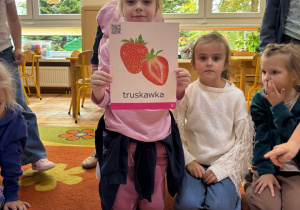 Dzieci oglądają i wskazują ilustracje przedstawiające warzywa i owoce