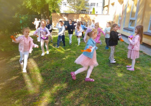 Dzieci bawią się w ogrodzie przedszkolnym rakietami wykonanymi z papieru