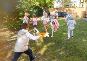Dzieci bawią się w ogrodzie przedszkolnym rakietami wykonanymi z papieru