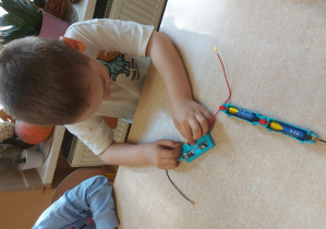 Dziecko buduje obwód elektryczny z użyciem żarówki