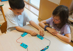 Dzieci budują obwód elektryczny z użyciem żarówki