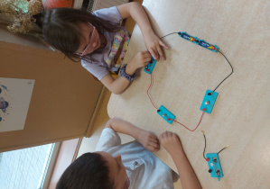 Dzieci budują obwód elektryczny z użyciem żarówki
