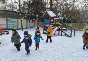 Dzieci na placu zabaw korzystają z uroków zimowej aury