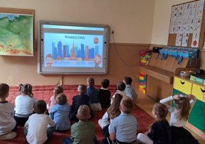 Dzieci rozwiazują zagadki o symbolach narodowych wyświetlane na tablicy interaktywnej
