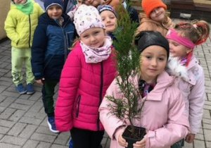 Dzieci idą sadzić krzew w ogrodzie przedszkolnym