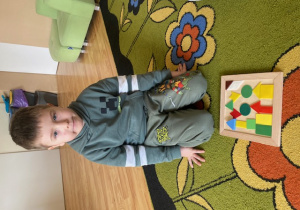 Chłopiec układa mozaikę geometryczną