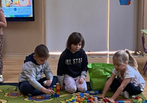Dzieci układają na podłodze klocki