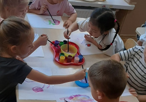 Dzieci wykonują pracę plastyczną farbami