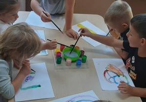 Dzieci wykonują pracę plastyczną farbami