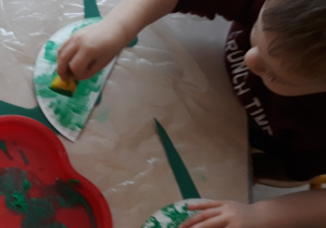 Chłopiec wykonuje dinozaura z papierowego talerzyka