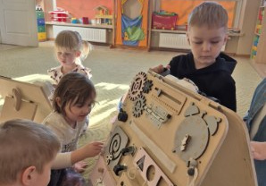 Dzieci bawią się tablicami manualno-sensorycznymi